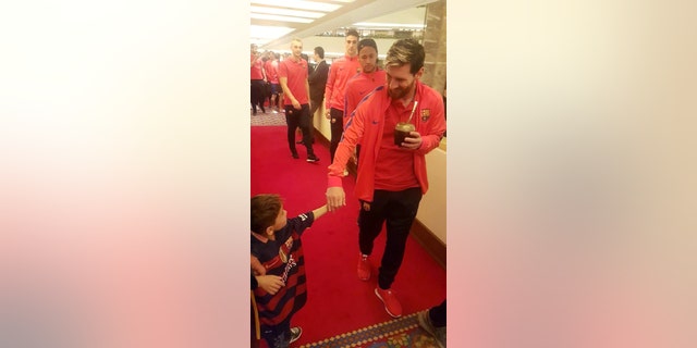In this Tuesday, Dec. 13, 2016 photo released by The Supreme Committee for Delivery & Legacy, SC, Lionel Messi holds the hand of Murtaza Ahmady in Doha, Qatar. Murtaza made a special trip from Afghanistan to Qatar, where Messi was with his Barcelona teammates to play a friendly match against Al Ahli on Tuesday. (The Supreme Committee for Delivery & Legacy, SC via AP)
