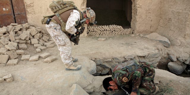 FILE - In this Saturday, Oct. 31, 2009 file photo, a member of U.S. special operations forces and an Afghan National Army soldier search for roadside bombs during a joint patrol in Shewan, a former Taliban stronghold in Afghanistan's Farah province.
