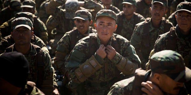 Nov. 26, 2013: An Afghan army soldier adjusts his uniform during an outdoor lesson at a training facility in the outskirts of Kabul, Afghanistan.