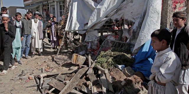Oct. 27, 2013: Afghans look at wreckage after a roadside bomb explosion went off on the outskirts of Kabul, Afghanistan. An Afghan official and witnesses say a roadside bomb, apparently targeting a group of soldiers, has killed a civilian in a market in the capital Kabul, the bomb went off Sunday as soldiers and officers for their vehicle to take them toward their work place.