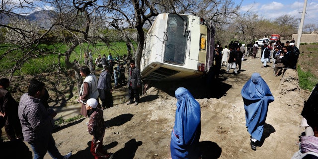 In this Monday, April 11, 2016. file, photo, Afghan women walk past a damaged bus after a roadside bomb explosion on the outskirts of Kabul, Afghanistan, The Afghan Taliban have announced the start of their warm-weather fighting season, an annual declaration that marks the launch of a summer of violence. (AP Photo/Rahmat Gul)