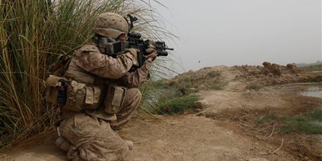 A U.S. Marine of 3rd Platoon, Kilo Company, 3/4 Marines, covers other Marines carrying boxes of U.S. Mail into their small outpost, Patrol Base 302, in Helmand province, southern Afghanistan, Friday, Aug. 26, 2011.
