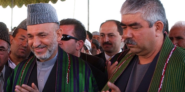 Sept. 26, 2004 file photo, Afghan President Hamid Karzai, left, accompanied by the presidential candidate and regional commander General Abdul Rashid Dostum applaud during his visit to Shiberghan, about 400 kilometers (250 miles) northwest of the capital Kabul.