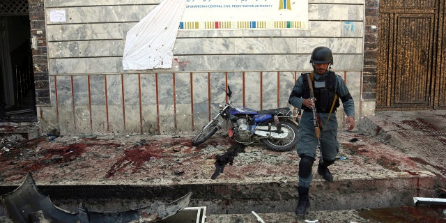 An Afghan police walks outside a voter registration center which was attacked by a suicide bomber in Kabul, Afghanistan, Sunday, April 22, 2018.
