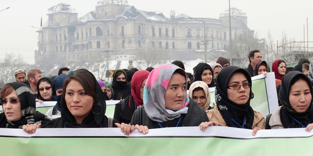 Feb. 14, 2013: Afghan women carry a banner during a march calling for end of violence against women, in Kabul, with the Darul Aman palace seen in the background, Afghanistan.