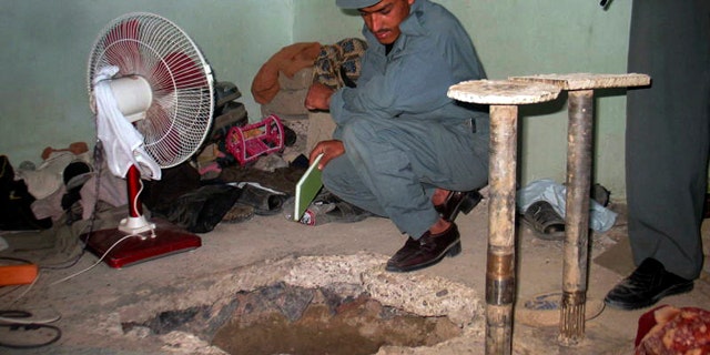 An Afghan policeman takes a look at the opening of tunnel at the main prison in Kandahar, Afghanistan, which prisoners escaped through on Monday, April 25, 2011. Taliban insurgents dug a more than 1,050-foot tunnel underground and into the main jail in Kandahar city and whisked out more than 450 prisoners, most of whom were Taliban fighters, officials and the insurgents said Monday. (AP)