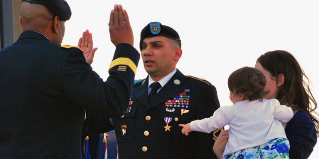 April 5, 2013: Sgt. 1st Class Matthew Loheide re-enlists in the Army at Fort Campbell, Ky., while his daughter, Annabella, held by Marianne Loheide, points to his Silver Star. Loheide received the Silver Star for his actions to evacuate wounded soldiers while in Afghanistan in 2010.