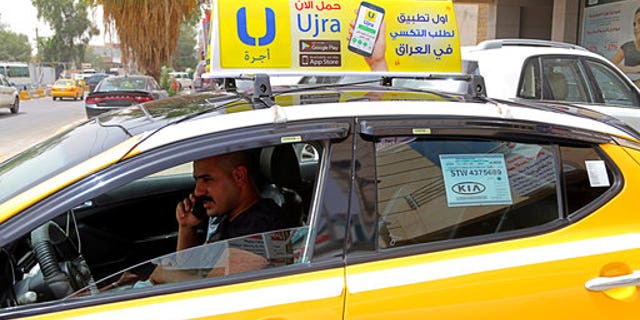 In this Monday, May 1, 2017 photo, Ali Raad, a taxi driver who workes for the ride-hailing app Ujra, receives a call from a customer, in Baghdad, Iraq. Tech-savvy Iraqi entrepreneurs are finding success in creating companies that use smartphone apps inspired by such foreign businesses as food ordering and ride sharing. This comes at a time when the government is looking to the private sector to create more jobs. (AP Photo/Karim Kadim)