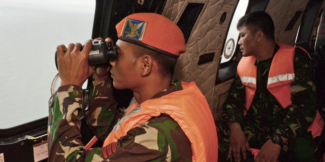 Jan. 1, 2015: A crew member of an Indonesian Air Force Super Puma helicopter of 6th Air Squadron uses a pair of binoculars to scan the horizon during a search operation for the victims of AirAsia Flight 8501 over Java Sea, Indonesia