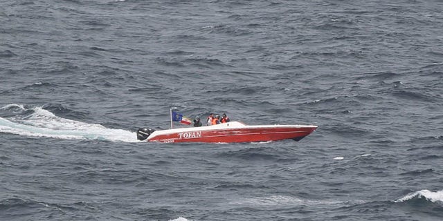 In this Tuesday, March 21, 2017 photograph, members of Iran's paramilitary Revolutionary Guard watch the USS George H.W. Bush as it travels through the Strait of Hormuz. The arrival of the nuclear-powered aircraft carrier to the Persian Gulf marks the first such deployment under new U.S. President Donald Trump. (AP Photo/Jon Gambrell)