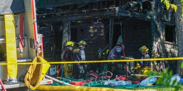 Firefighters investigate the remains of a burned home in Akron, Ohio on Monday, May 15, 2017. Firefighters said multiple people died in the fire at the home. (AP photo/Dake Kang)