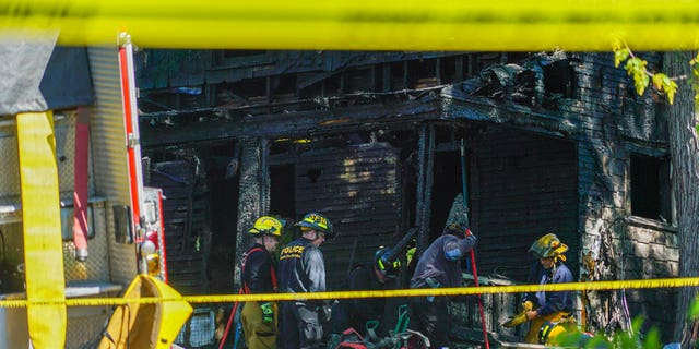 Firefighters investigate the remains of a burned home in Akron, Ohio on Monday, May 15, 2017. Firefighters said multiple people died in the fire at the home. (AP photo/Dake Kang)
