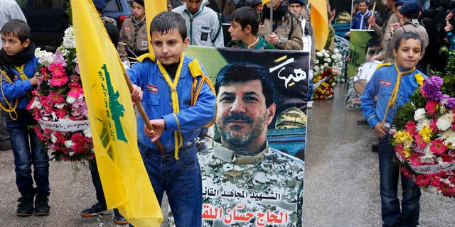 Hezbollah boy scouts carry the party flags and a picture of Hezbollah commander Hassan al-Lakkis during his funeral in Baalbeck, in Lebanon's Bekaa valley. (Reuters)