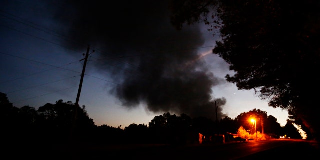 Light from a light pole shows a house near a plume of smoke from a Colonial Pipeline explosion, Monday, Oct. 31, 2016, in Helena, Ala.