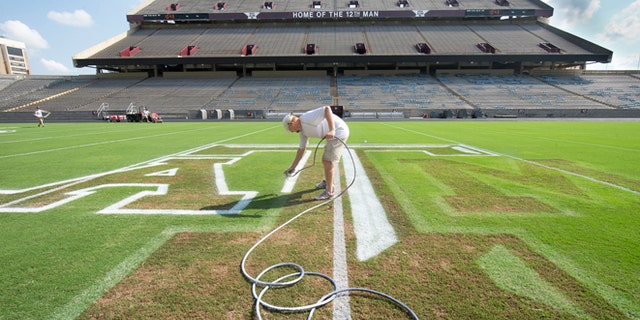 Sept. 12, 2013: Jaxon Bailey paints the outline of the midfield logo at Kyle Field in College Station, Texas, in preparation for Saturday's NCAA college football game between Texas A&M and Alabama. (AP/Bryan-College Station Eagle, Stuart Villanueva)