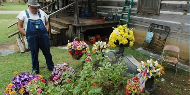 Aug. 10, 2012: James Davis, 73, stands over the grave of his wife, Patsy, in the front yard of the home they shared in Stevenson, Ala.