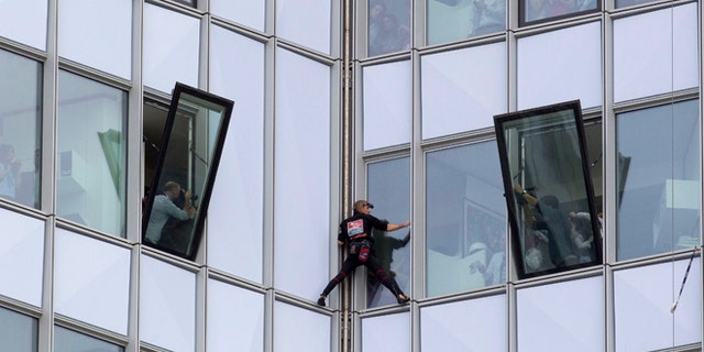 May 10, 2012: People look out of their windows as French urban climber Alain Robert, known as 'Spiderman', climbs up the 758 feet high First Tower, the tallest skyscraper in France, outside Paris.