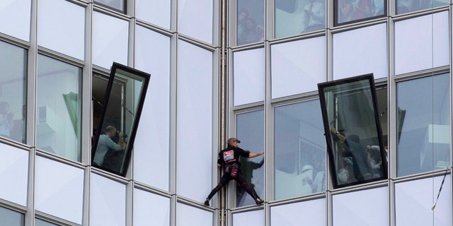 May 10, 2012: People look out of their windows as French urban climber Alain Robert, known as 'Spiderman', climbs up the 758 feet high First Tower, the tallest skyscraper in France, outside Paris.