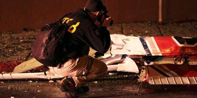 Dec. 29, 2015: A National Transportation Safety Board investigator takes photos at the scene of an aircraft crash in Anchorage, Ak. A small plane clipped a downtown Anchorage office building and then slammed into a nearby commercial building early Tuesday, igniting a fire and killing the pilot, authorities said. (Loren Holmes/Alaska Dispatch News via AP)