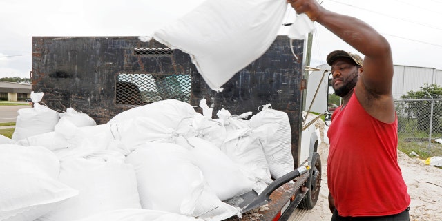 Travis Lee loads filled sand bags onto a truck bed as he and a co-worker prepare to protect the storage company they work at, Saturday, May 26, 2018 in Gulfport, Miss.