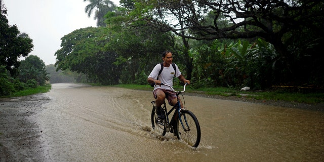 A man rides a bicycle down a flooded road as Subtropical Storm Alberto passes by the west coast of Cuba, in Bahia Honda, Cuba, May 26, 2018.
