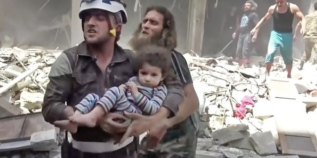 April 28, 2016: In this image made from video and posted online from Validated UGC, a Civil Defense worker carries a child after airstrikes hit Aleppo, Syria.