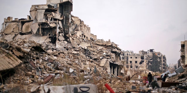 December 17, 2016: People carry belongings as they walk on the rubble of damaged buildings in the government controlled area of Aleppo, Syria.