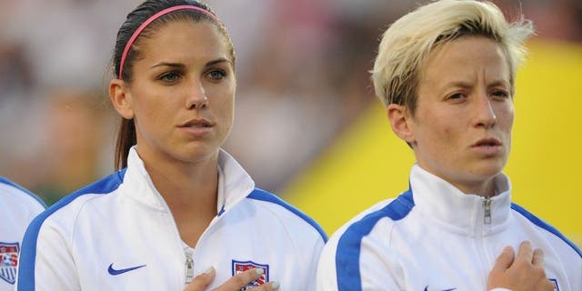Lauren Holiday, Alex Morgan, and Megan Rapinoe of the U.S. women's national team stand at attention during the National Anthem prior to their match against the Swiss women's national team at WakeMed Soccer Park on August 20, 2014, in Cary, North Carolina. (Photo by Lance King/Getty Images)