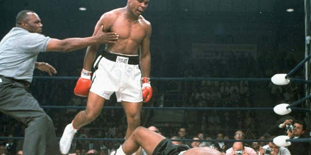 May 25, 1965: Heavyweight champion Muhammad Ali is held back by referee Joe Walcott after Ali dropped challenger Sonny Liston less than two minutes into the first round of their heavyweight title fight.