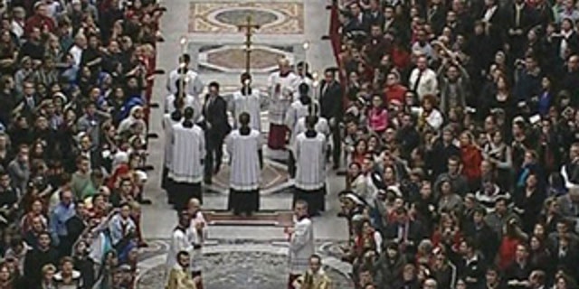 In this image made from Vatican television via APTN, Vatican security, at center of aisle in black, make their way towards Pope Benedict XVI, not seen, after he was knocked down during Christmas Mass in St. Peter's Basilica at the Vatican, Thursday, Dec. 24, 2009. A woman jumped the barriers in St. Peter's Basilica and knocked down the pontiff as he walked down the main aisle to begin Christmas Eve Mass on Thursday, a Vatican spokesman said. The Rev. Ciro Benedettini said the 82-year-old pope quickly got up and was unhurt. (AP Photo/CTV via APTN) ** AP CLIENTS ONLY **