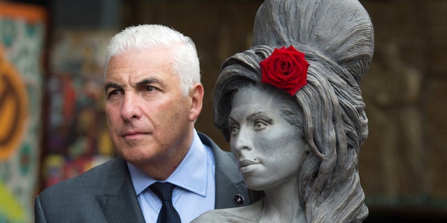 Winehouse's father with a statue of the singer in England.