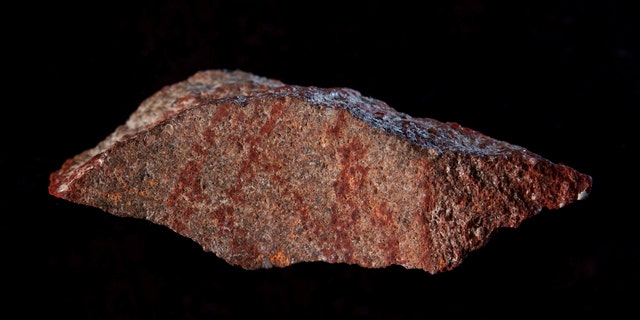 This undated photo provided by Craig Foster in September 2018 shows a drawing made with ochre pigment on silcrete stone, found in the Blombos Cave east of Cape Town, South Africa. In a report released on Wednesday, Sept. 12, 2018, scientists say this tiny 73,000-year-old sketch found in a South African cave is the oldest known drawing. (Craig Foster via AP)