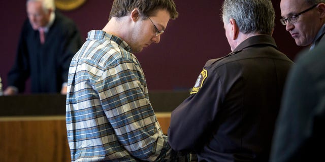 Andrew Maison looks down as he is handcuffed.