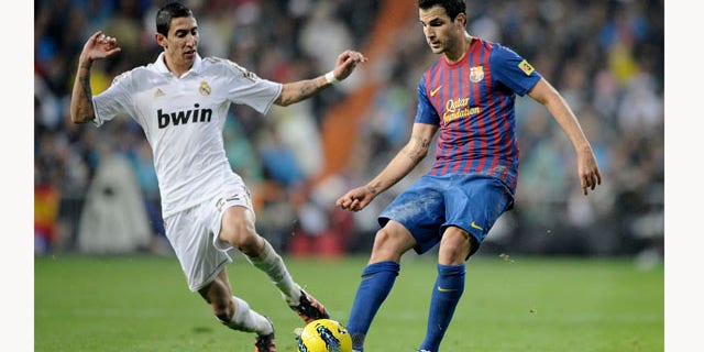 Real Madrid's Angel Di Maria from Argentina, left, duels for the ball with Barcelona's Cesc Fabregas, right, during their Spanish La Liga soccer match at the Santiago Bernabeu stadium, in Madrid, Saturday, Dec. 10, 2011. (AP Photo/Daniel Ochoa de Olza)