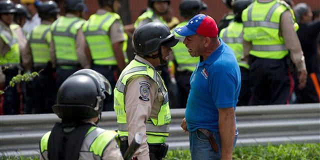 An anti-government demonstrator argues with a Bolivarian National Police officer during a march toward the headquarters of the national electoral body, CNE, in Caracas, Venezuela, Wednesday, May 18, 2016. The opposition was blocked from marching to the CNE as they demand the government allow it to pursue a recall referendum against Venezuela's President Nicolas Maduro. (AP Photo/Fernando Llano)