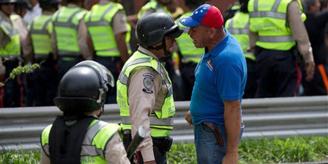 An anti-government demonstrator argues with a Bolivarian National Police officer during a march toward the headquarters of the national electoral body, CNE, in Caracas, Venezuela, Wednesday, May 18, 2016. The opposition was blocked from marching to the CNE as they demand the government allow it to pursue a recall referendum against Venezuela's President Nicolas Maduro. (AP Photo/Fernando Llano)