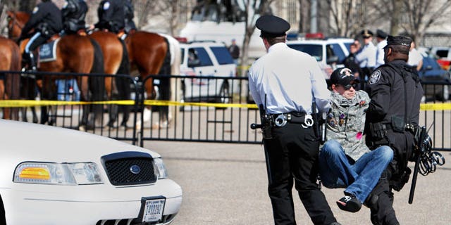 A unidentified protester lifts his legs as he is arrested by U.S. Park Police near the White House while protesting against war on the 8th anniversary of the Iraq invasion in Washington, on Saturday, March 19, 2011. (AP)