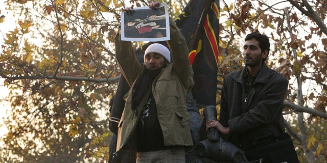 Nov. 29: An Iranian protester holds a picture of Queen Elizabeth to tear up on the gate of the British embassy in Tehran.