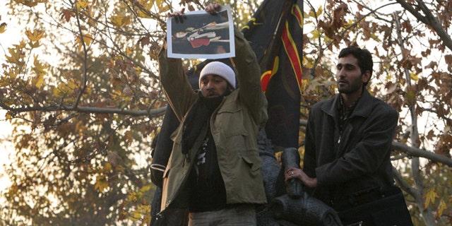 Nov. 29: An Iranian protester holds a picture of Queen Elizabeth to tear up on the gate of the British embassy in Tehran.
