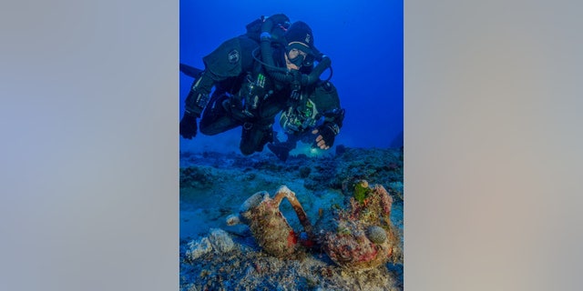 An archaeologist swims over artifacts at the site of the Antikythera shipwreck. In 2015, researchers pulled 50 new objects from the depths as part of the first scientific excavation of the wreck site.