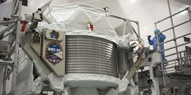 Technicians examine the $2 billion Alpha Magnetic Spectrometer instrument in a work stand ahead of its planned launch on NASA's space shuttle Endeavour. The AMS instrument will search for cosmic rays from the International Space Station.