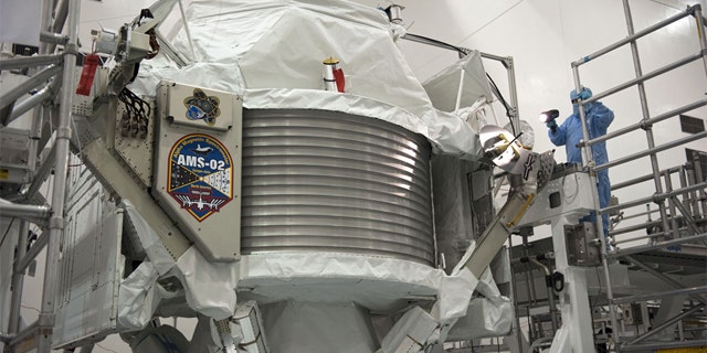 Technicians examine the $2 billion Alpha Magnetic Spectrometer instrument in a work stand ahead of its planned launch on NASA's space shuttle Endeavour. The AMS instrument will search for cosmic rays from the International Space Station.