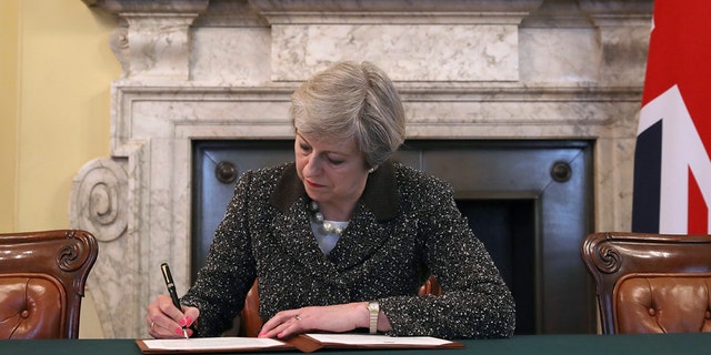 Britain's Prime Minister Theresa May signs the official letter to European Council President Donald Tusk, in 10 Downing Street, London, Tuesday March 28, 2017, invoking Article 50 of the bloc's key treaty, the formal start of exit negotiations. Britons voted in June to leave the bloc after four decades of membership. (Christopher Furlong/Pool Photo via AP)