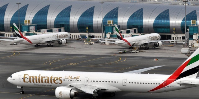 FILE- In this Wednesday, March 22, 2017 file photo, an Emirates plane taxis to a gate at Dubai International Airport at Dubai International Airport in Dubai, United Arab Emirates. The Middle East's biggest airline says it is reducing flights to the United States because of a drop in demand caused by tougher U.S. security measures and attempts by the Trump administration to ban travelers from a number of Muslim-majority nations. (AP Photo/Adam Schreck, File)