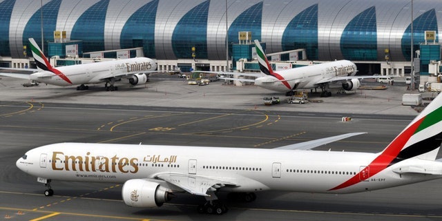FILE- In this Wednesday, March 22, 2017 file photo, an Emirates plane taxis to a gate at Dubai International Airport at Dubai International Airport in Dubai, United Arab Emirates. The Middle East's biggest airline says it is reducing flights to the United States because of a drop in demand caused by tougher U.S. security measures and attempts by the Trump administration to ban travelers from a number of Muslim-majority nations. (AP Photo/Adam Schreck, File)