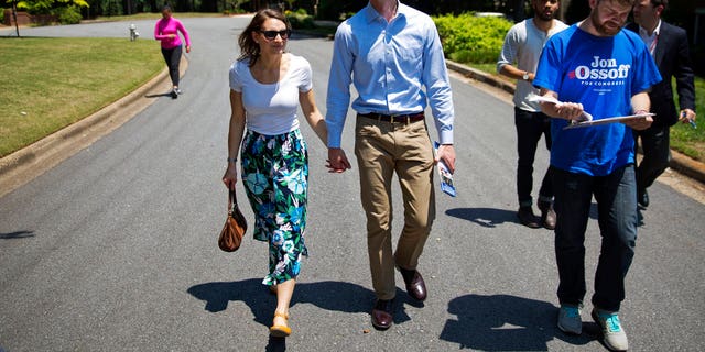 Jon Ossoff, center, a 30-year-old Democrat running for Congress in Georgia's traditionally conservative 6th Congressional District, and fiancee Alisha Kramer, left, walk with organizer Eliot Beckham, right, while campaigning in Sandy Springs, Ga., Thursday, May 11, 2017. Ossoff's fortunes in a June 20 matchup with Republican Karen Handel will be an early test of how the Republicans' vote to gut the Affordable Care Act and President Donald Trump's decision to fire the FBI director are playing with voters. Both parties see the Georgia race as an indicator for the 2018 midterm elections. (AP Photo/David Goldman)