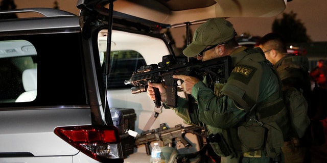 An ATF agent checks his weapon as he gets ready for a raid Wednesday morning, May 17, 2017, in Los Angeles. Hundreds of federal and local law enforcement fanned out across Los Angeles, serving arrest and search warrants as part of a three-year investigation into the violent and brutal street gang MS-13. (AP Photo/Jae C. Hong)