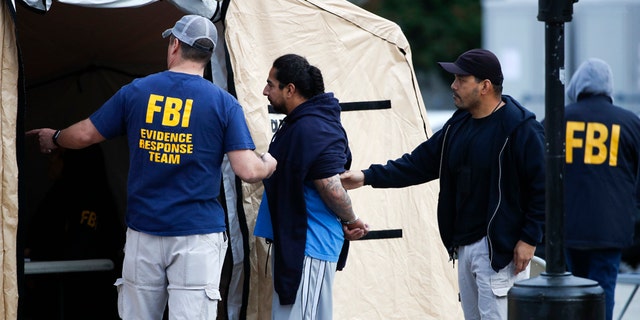 A man is taken into custody by FBI agents Wednesday, May 17, 2017, in Los Angeles. Hundreds of federal and local law enforcement fanned out across Los Angeles, serving arrest and search warrants as part of a three-year investigation into the violent and brutal street gang MS-13. (AP Photo/Jae C. Hong)