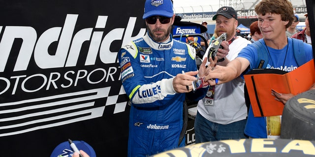 Jimmie Johnson signs autographs for fans after practice for the NASCAR Cup series auto race, Saturday, June 3, 2017, at Dover International Speedway in Dover, Del. (AP Photo/Nick Wass)