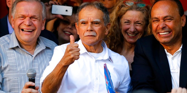 FILE- In this May 18, 2017 file photo, Puerto Rican nationalist Oscar Lopez Rivera, center, reacts to the crowd as his brother Jose, left, and U.S. Rep Luis Gutierrez, D-Ill., join him at a gathering in his honor in Chicago's Humboldt Park neighborhood. New York City's annual Puerto Rican Day parade will take place under a cloud of controversy this year because of a decision by organizers to honor Lopez Rivera, who spent decades in prison because of his involvement with the terrorist group FALN. (AP Photo/Charles Rex Arbogast, File)